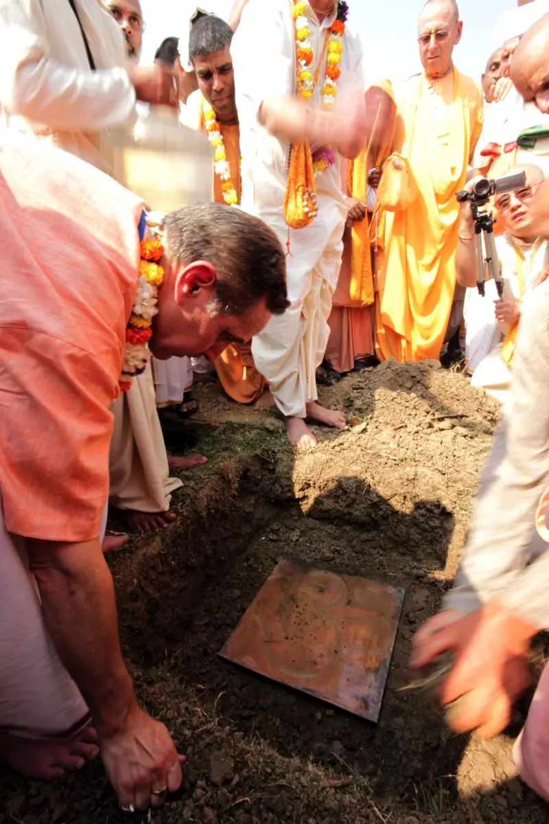 Амбариша Прабху кладет одну из больших медных пластин с вырезанными на ней различными ведическими знаками в одном из четырех углов строительной площадки храма.